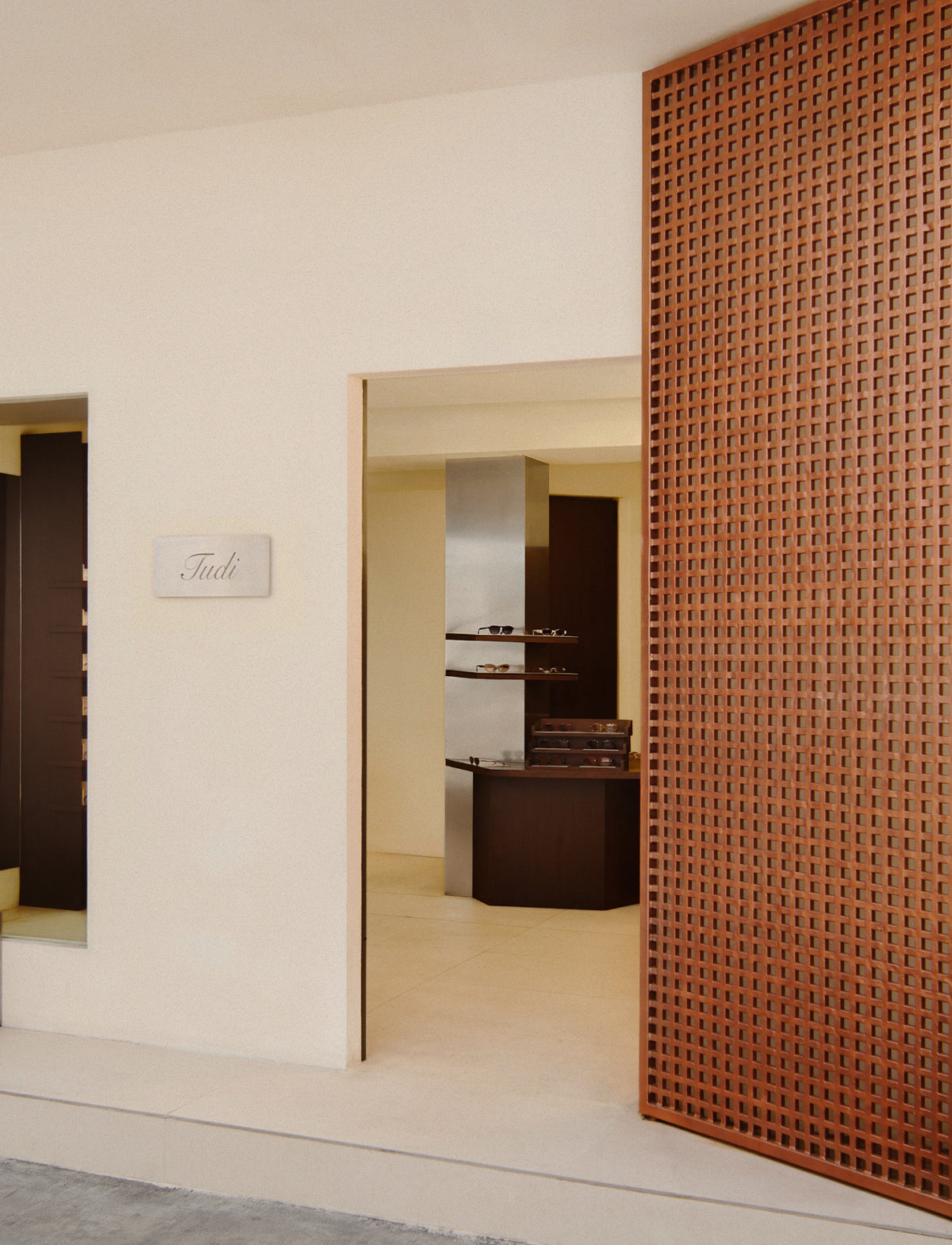 TUDI store entrance beside a perforated terracotta wall