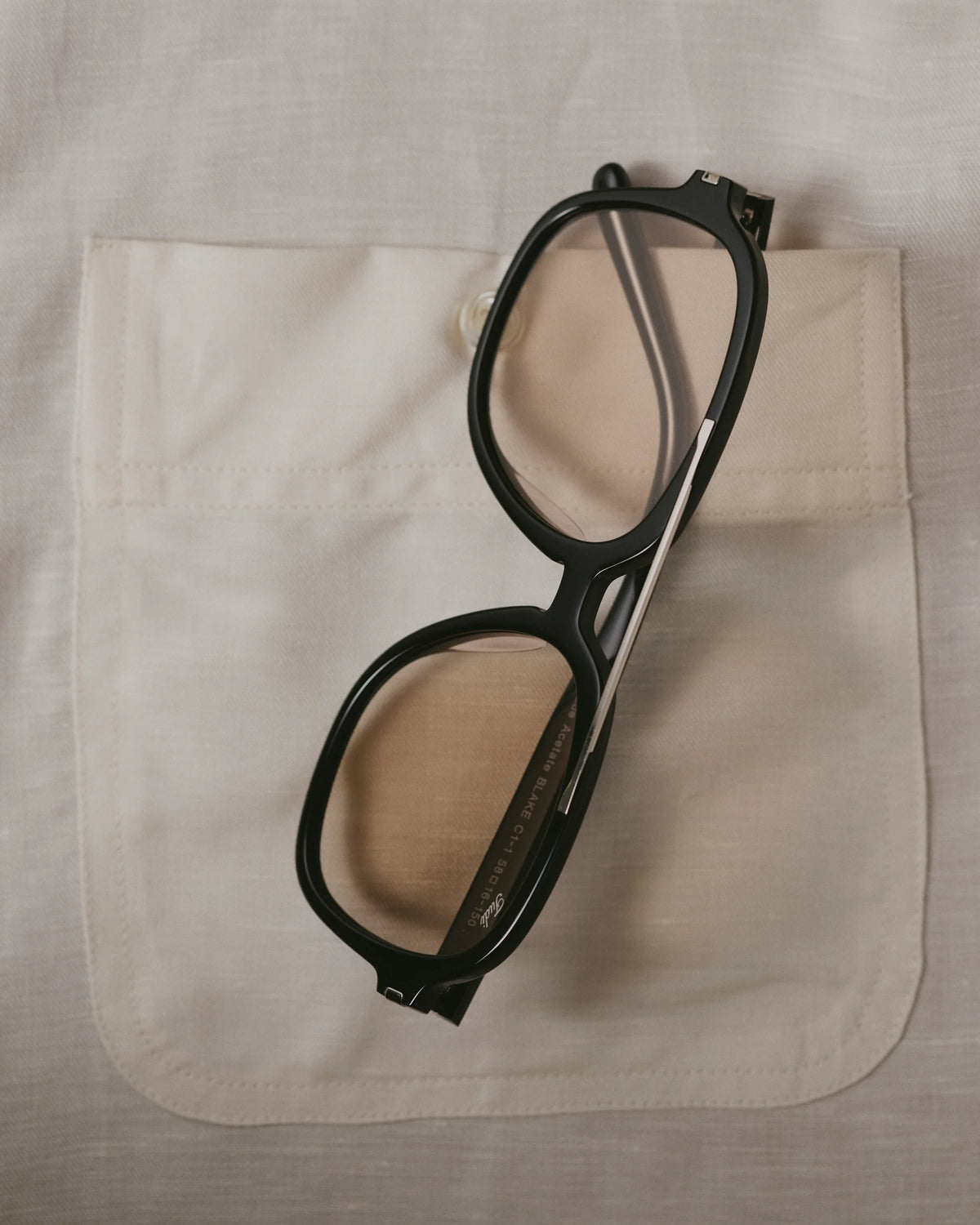 TUDI Blake eyewear, styled still life, black frame; pale tinted lenses