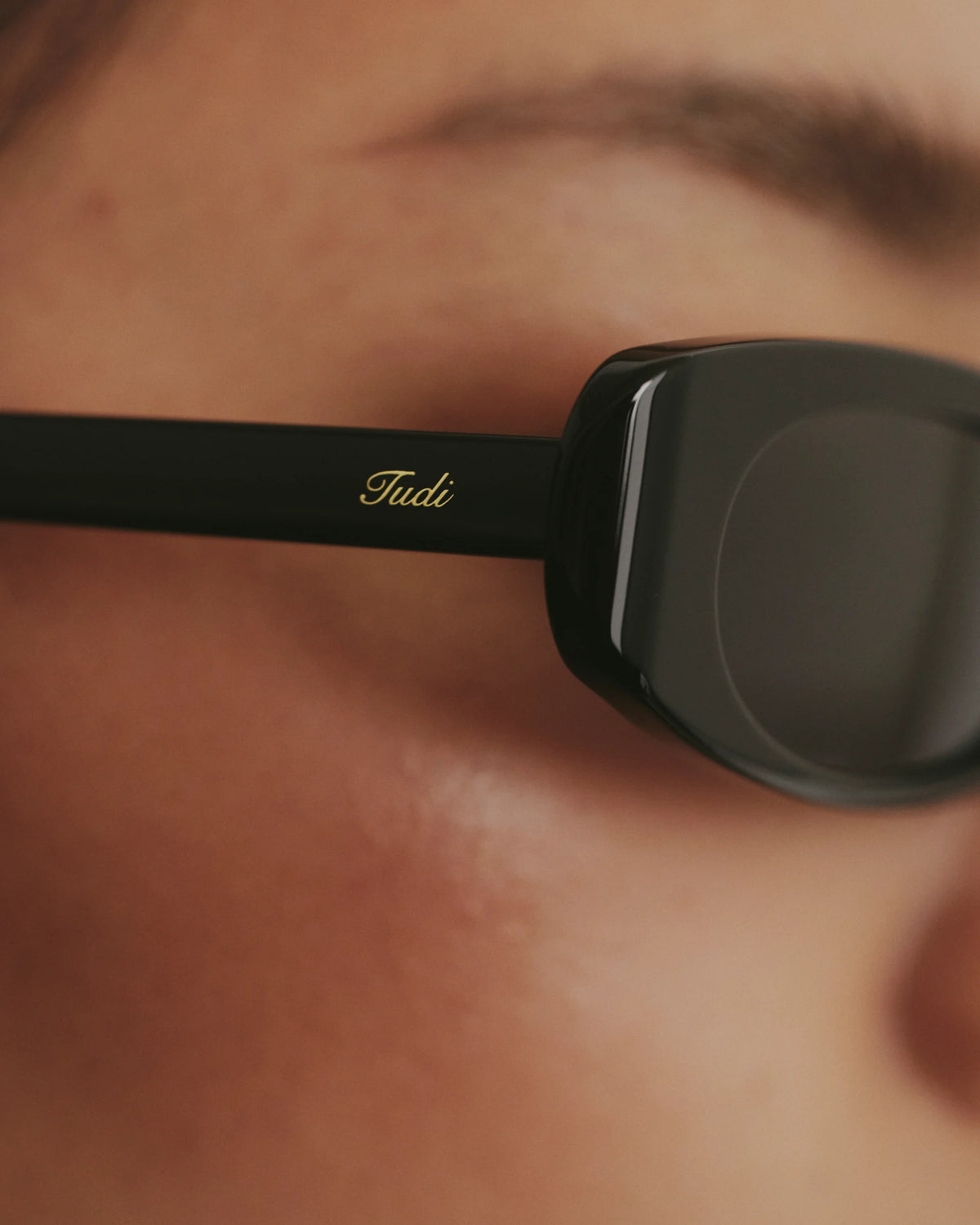 TUDI Kai eyewear, worn detail, black frame; dark lenses