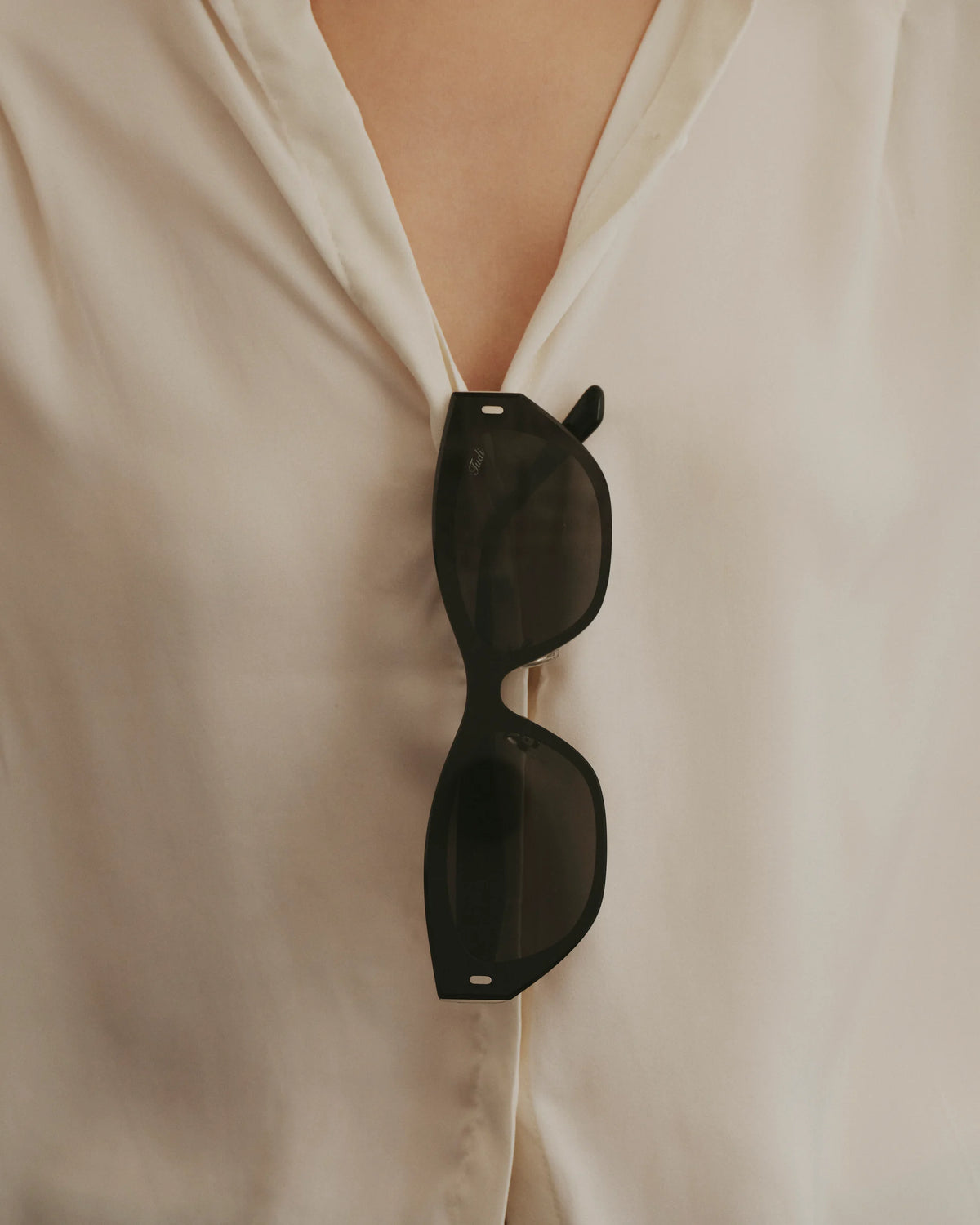 TUDI Molly eyewear, styled still life, black front; dark lenses