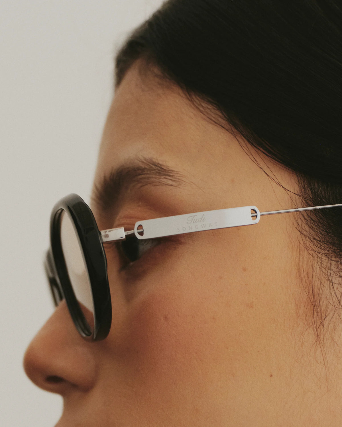 TUDI Nook eyewear, worn detail, black frame; rose-tinted lenses